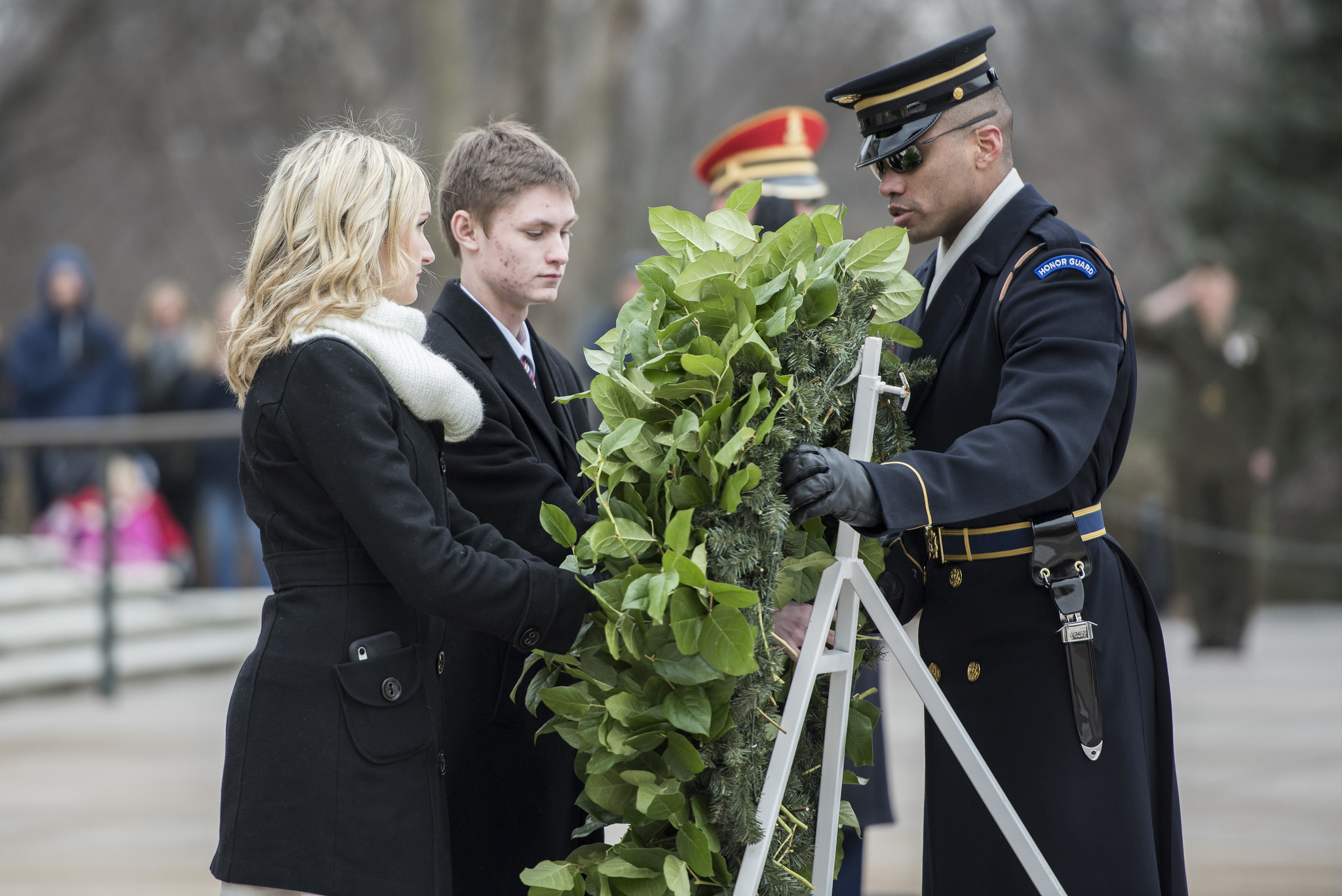 Two teenagers, wearing appropriate attire, participate in a wreath ceremony at the Tomb of the Unknown Soldier