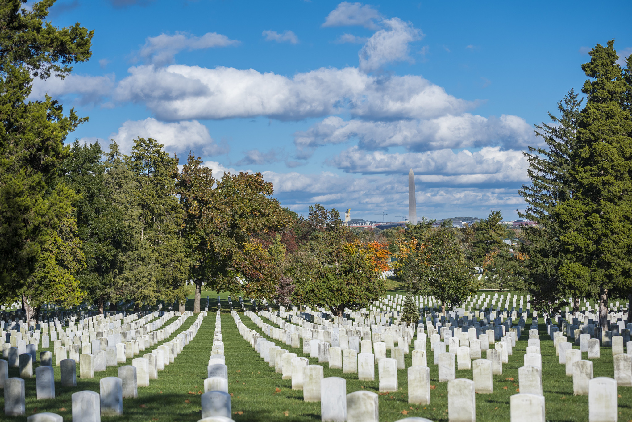 Rows of white gravestones at Arlington National Cemetery, with views of the Washington Monument in the distance