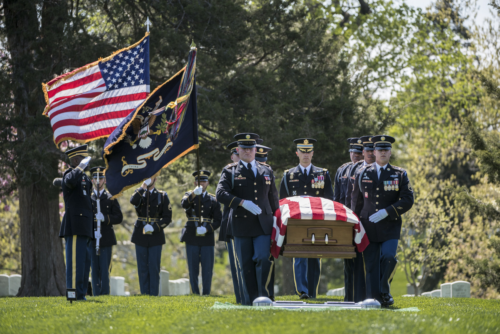 Soldiers in dress uniform carry a flag-draped casket